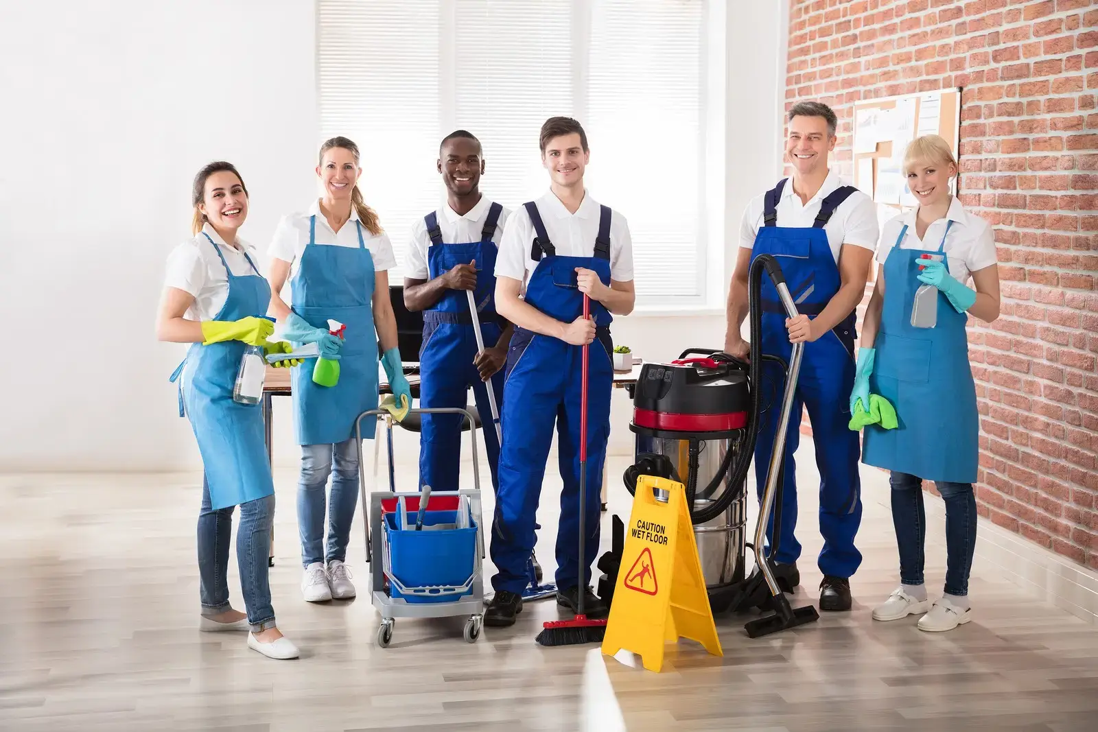 Professional cleaning team with equipment standing in modern office